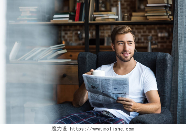 一个坐在沙发上看向窗外的男人男人在家里看报纸
